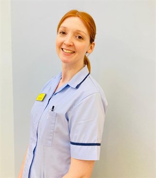 Karen Foster, a healthcare support worker at WHH. Image shows her from the waist up, turned slightly towards the camera. She is wearing a blue tunic uniform