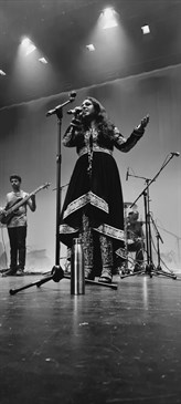 Rema Iyer performing at the concert. Black and white image showing Rema on stage with a microphone