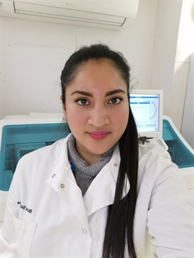 Estefany Davies, pictured wearing a lab coat with a computer behind her.