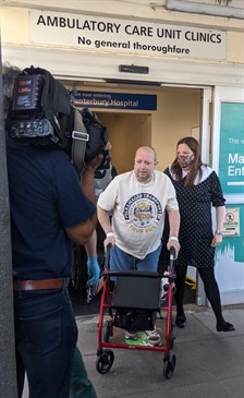 Alan Finch leaving hospital. He is pictured walking out of the Kent and Canterbury Hospital, being filmed by a cameraman. Next to him is his partner Claire Wickham