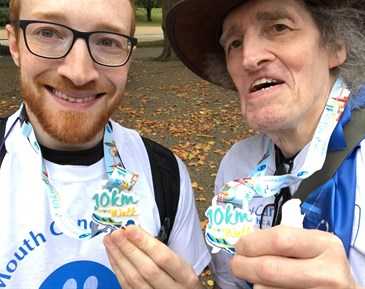 Anthony Page with his son Alex on a charity walk in 2019. The photo shows their head and shoulders; they are wearing mouth cancer t-shirts and holding medals.