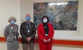 Avatar of Susan Acott, Shane McCoubrey and Dee Neligan with one of his pieces. Image shows them standing to the side of the work, which is hung in a recess in a hospital corridor. They are all wearing facemasks.