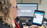 Avatar of Tina Elliott demonstrating how the remote clinic works. Image shows Tina holding an iPad which has a screen showing the patient's face and a diagram of a body. She is in a clinic environment.