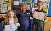 Avatar of Violet Hawkins, Mel Mears and Olivia Frisby. They are pictured in a school office. The girls are wearing school uniform and holding certificates, Mel is in the centre in a nurses' uniform