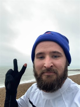 Ben Sackett, who is doing a run for East Kent Hospitals Charity. He is bearded, wearing a hat, and holding two fingers up in a v sign.