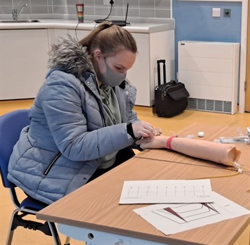 Christina Ames O'Regan pracitising inserting a needle into a fake arm as part of a clinic helping young people with diabetes and needle anxiety