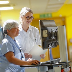 Nurses working on the critical care ward. Two are talking to each other and looking at a computer screen