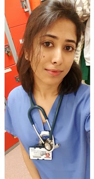 Divya Benny, one of the Trust's physician associates, in scrubs with a stethoscope around her neck. She is standing in a locker room.