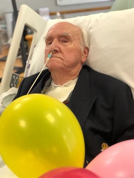 Donald Dusty Miller at his party. Photo shows him in a hospital bed with balloons in the foreground.