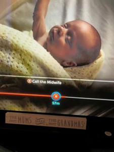 Screenshot of George appearing in Call the Midwife. Image shows a TV screen with a baby in a crib wrapped in a yellow blanket