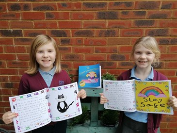 Isla and Maisie with the book they helped illustrate, PS Thank You Very Much. They are pictured wearing school uniform holding the book