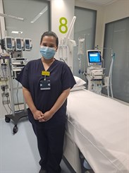 Izza Ciocon, band 6 critical care nurse at WHH. Image shows her wearing scrubs and a mask in a critical care bed space