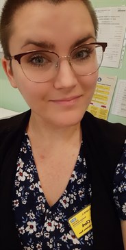 Jade Clark, children's diabetes nurse who was diagnosed with Type 1 diabetes aged 10. Photo shows her in a floral dress and black cardigan, looking at the camera. She is wearing glasses.