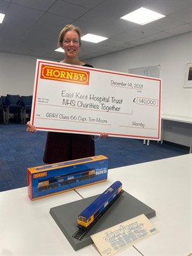 Jess Evans with the cheque from Hornby Hobbies and the limited edition engine. Photo shows Jess holding a giant cheque made out to EKHUFT and NHS Charities Together for £140,000. On the table in front of her is the limited edition engine and box
