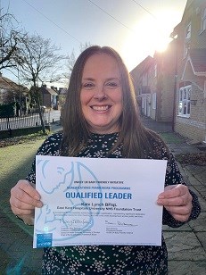 Kate Lynch, pictured outside with a road and houses behind her, with her certificate. She has been named as one of just seven Baby Friendly Initiative Qualified Leaders nationwide