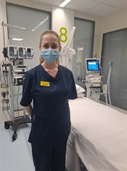 Kodie Waters, Band 6 critical care nurse. Image shows her in scrubs and a mask in a critical care bed space