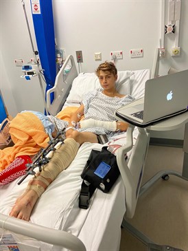Leyton Bridgewater, who features in the trauma documentary Emergency. He is pictured in a hospital bed with a blanket over one leg and a laptop on a table in front of him