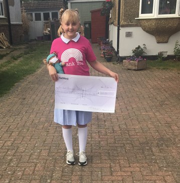 Maddie Burgess who raised £750 for East Kent Hospitals Charity outside her house with a cheque