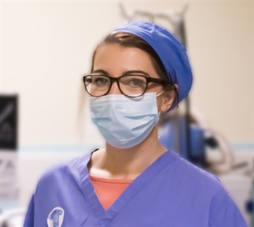 ODP Sally Csuka. Photo shows her wearing scrubs, a mask and a cap, looking at the camera in an operating theatre environment