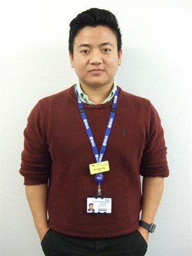 Oman Rai, a doctor who completed work experience at the hospital where he now works. He is pictured wearing a dark jumper over a shirt, with an ID lanyard round his neck.