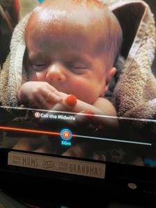 Screenshot of Oscar appearing in Call the Midwife. Image shows a baby wrapped in a towel with a woman's hand.