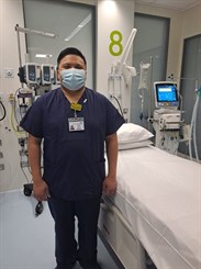 Ray Supilanas, band 6 critical care nurse at WHH. Image shows him wearing scrubs and a mask in a critical care bed space