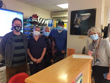 Robbie Graham, fourth from left, with his wife Sue, chief executive Susan Acott, right, and cardiac care staff Ivor Morris and Sorrel Withers. They are standing at a desk on the ward with the painting on the wall
