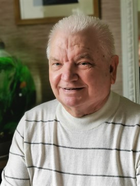 Robert Jones, one of the first patients to have robotic surgery for throat cancer. It is a head and shoulders shot and he is smiling at the camera, wearing a white jumper with dark stripes.