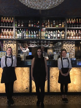 Rosemont restaurant staff. Photo shows three staff standing in front of a bar, with one man behind the bar putting a glass away. 