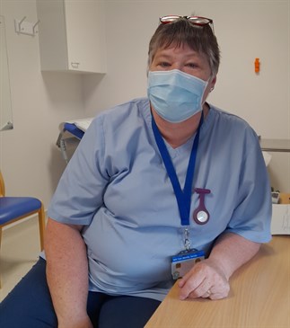 Roz Mallory who is retiring after 45 years. She is pictured in a clinic room wearing a uniform and face mask