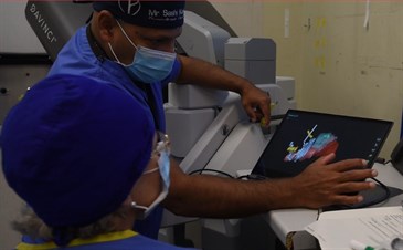 Sashi Kommu demonstrating 3D augmented images. Image shows Sashi in mask and surgical cap showing someone an image on a tablet screen