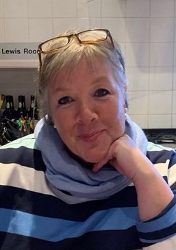 Sophie Pettifer, former nurse and hospital Governor, who has died after a battle with cancer. Image shows her inside, wearing a blue striped top and scarf with her glasses on her head