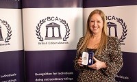 Avatar of Tracey Twyman, who received a British Citizen Award. She is pictured holding the award in front of a BCA backdrop