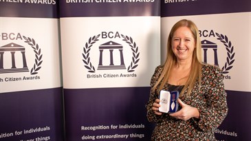 Tracey Twyman, who received a British Citizen Award. She is pictured holding the award in front of a BCA backdrop