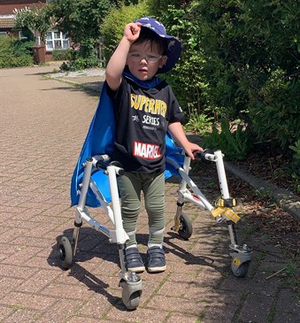 Vincent Simester, who has raised £500 with asponsored walk. He is pictured standing in a walking frame, wearing a Marvel superheroes top and cape