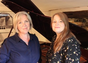 Vocal coaches Kerry Boyle and Cathy Robinson. They are pictured in front of a grand piano.