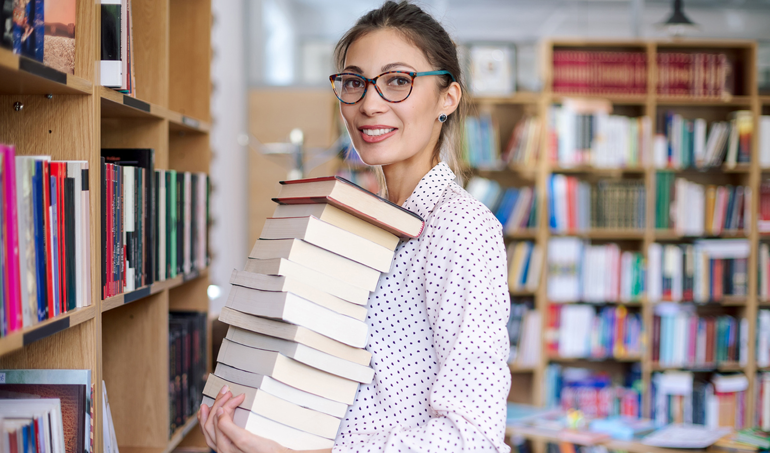 Woman holding a stack of books in a library