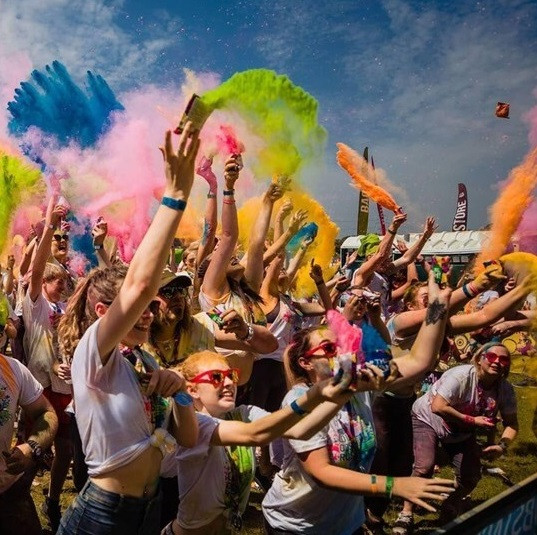 People taking part in a colour rush event - image shows a group of people in t-shirts throwing colour packets in the air