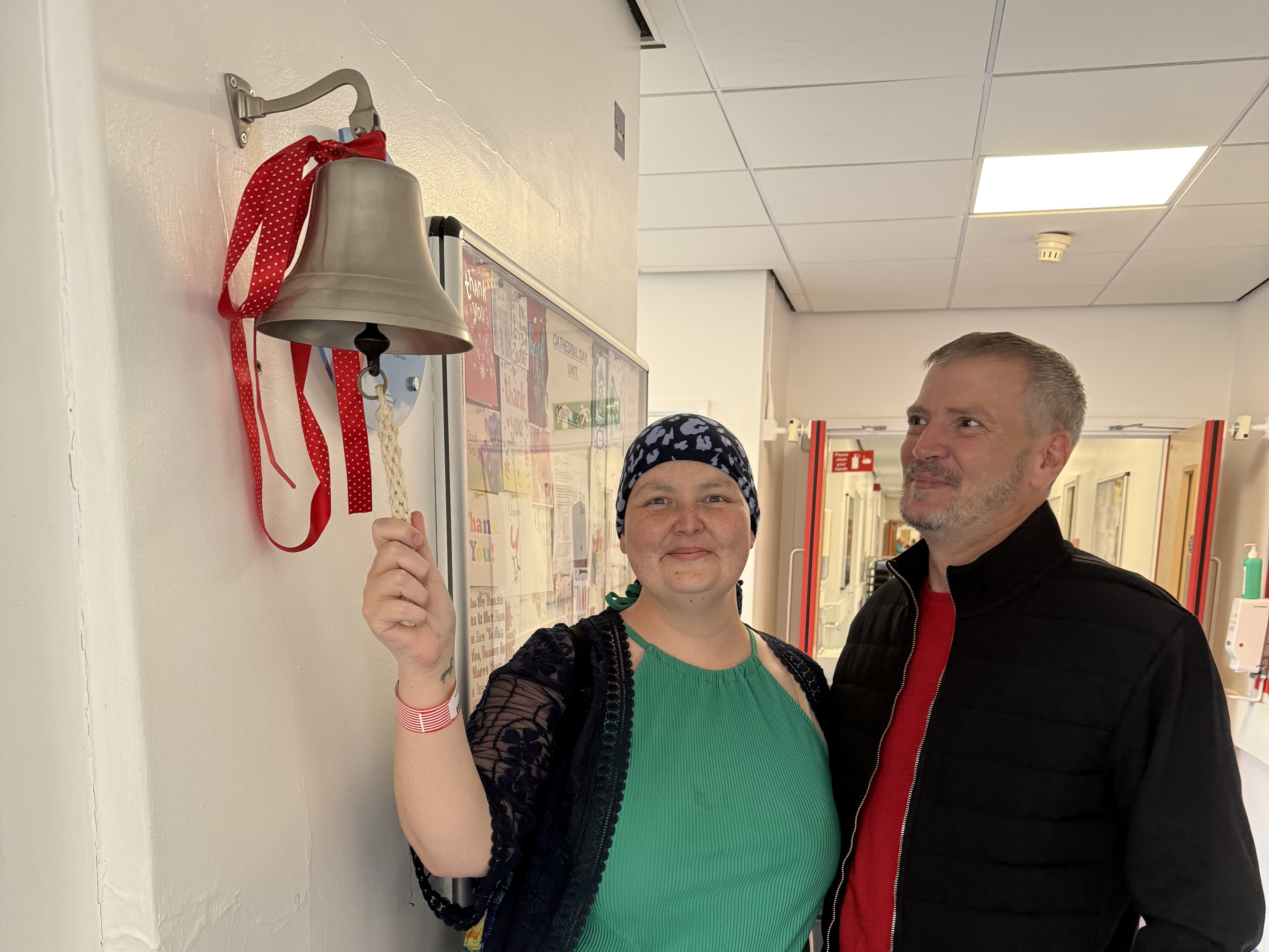 Chelsey rings the bell to signify the end of her chemotherapy treatment, watched by husband James