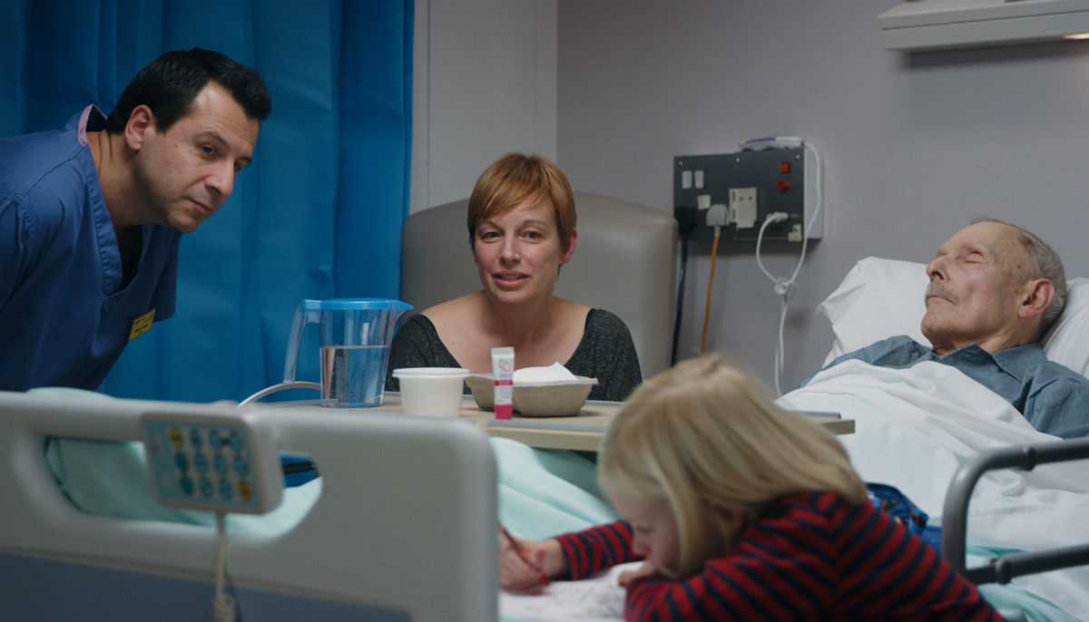 Still image from Caring with Compassion film showing family at patient's bedside.