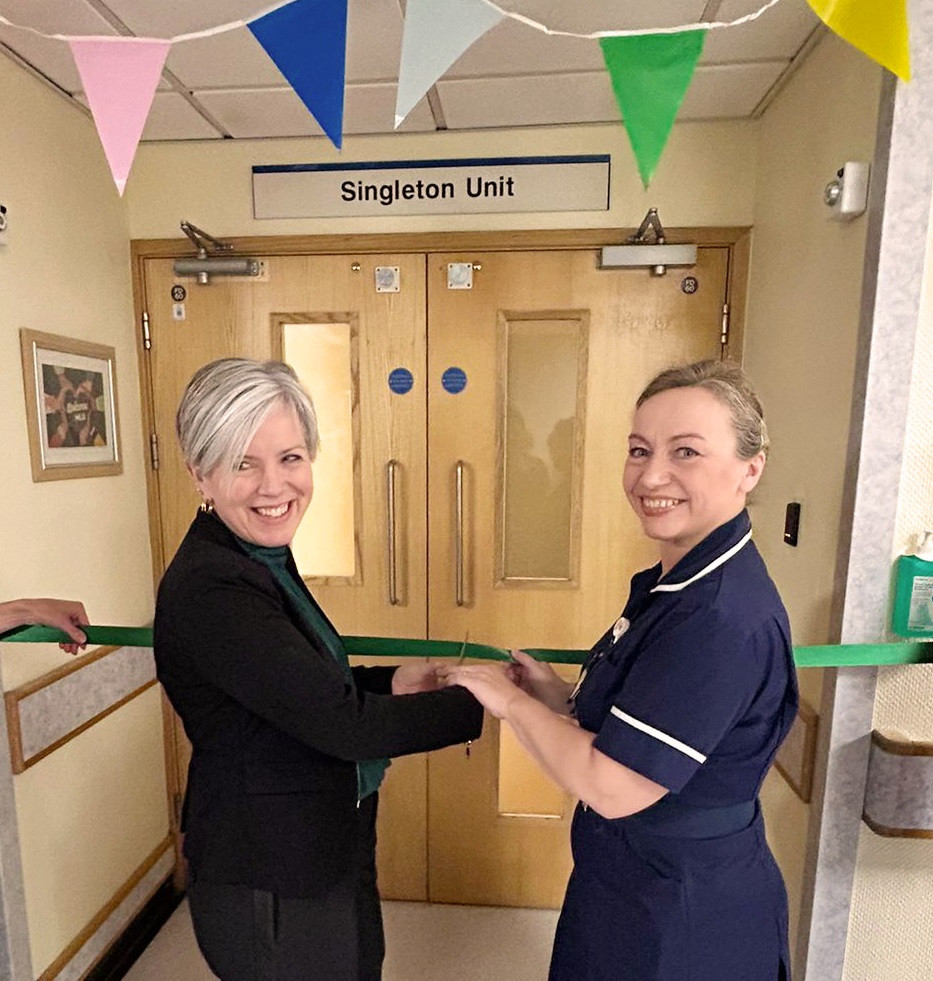 Two women cut a ribbon to officially open the SIngleton Unit