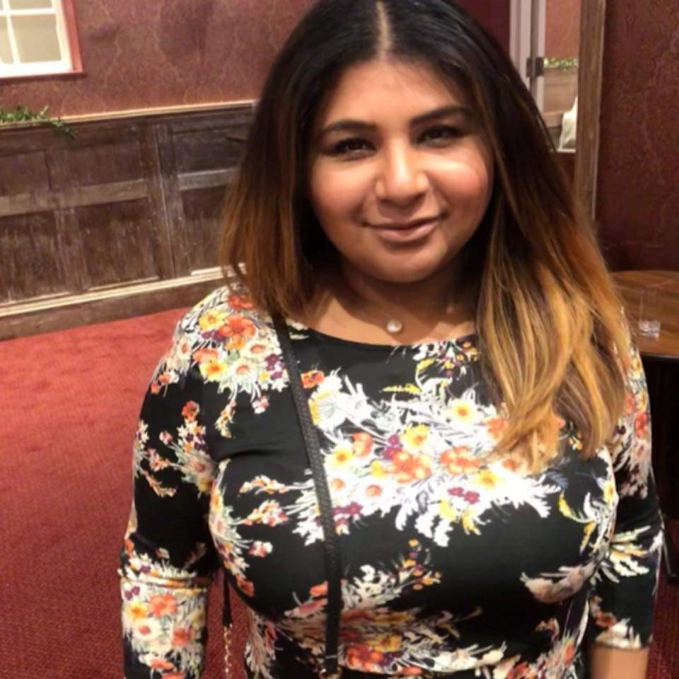 Dr Habiba 'Bee' Hajallie. She is wearing a black top with floral design and smiling at the camera