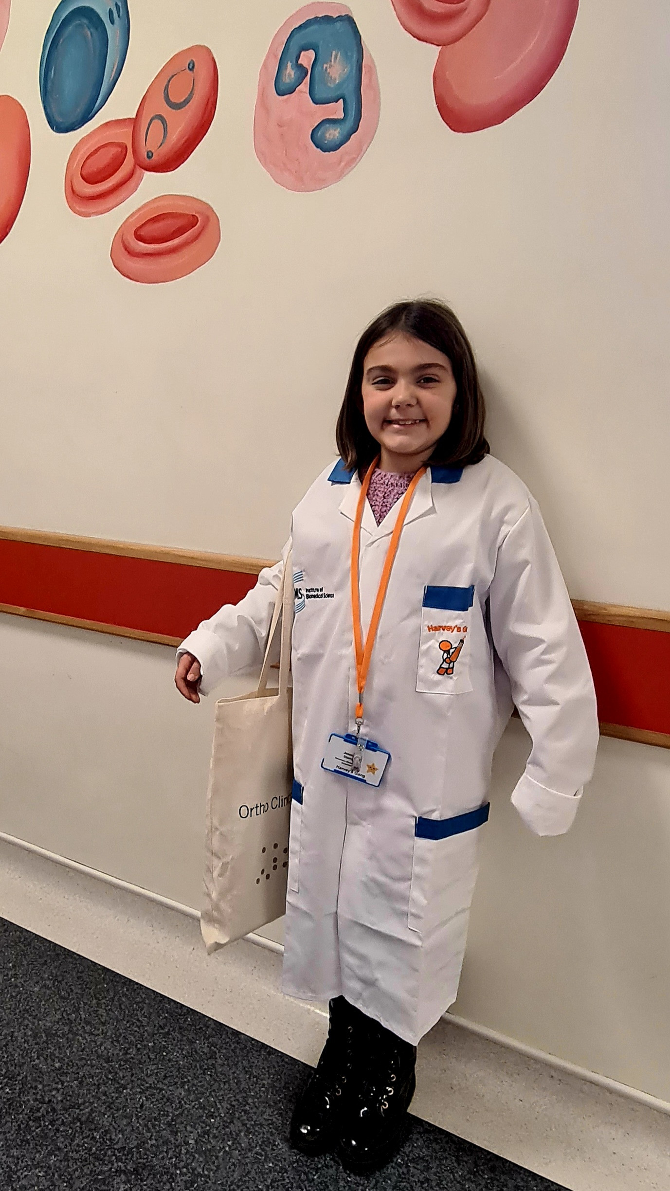 Jessica wearing her lab coat and lanyard and holding her goody bag