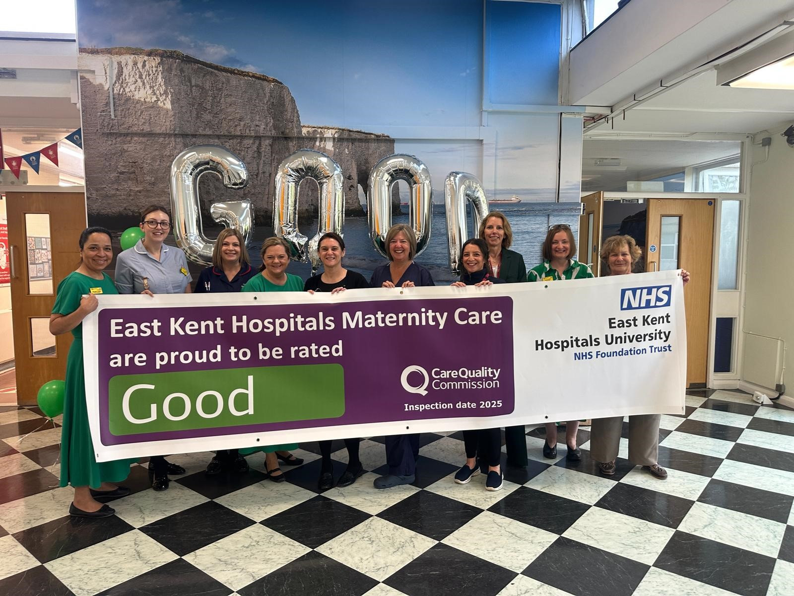 Some of the team at QEQM celebrating their win. They are holding a banner and balloons with the words good