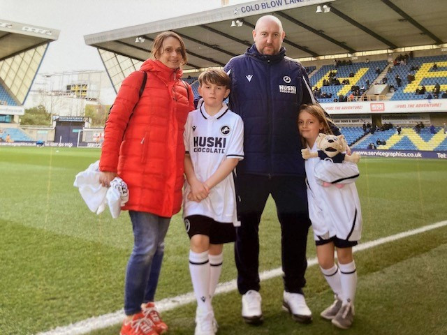 Tim with his wife and two children on a football pitch