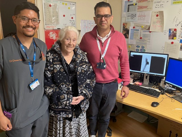 Valerie with Dexter Calencia, left, and Sandeep Bahia, right with an image of the aneurysm on screen