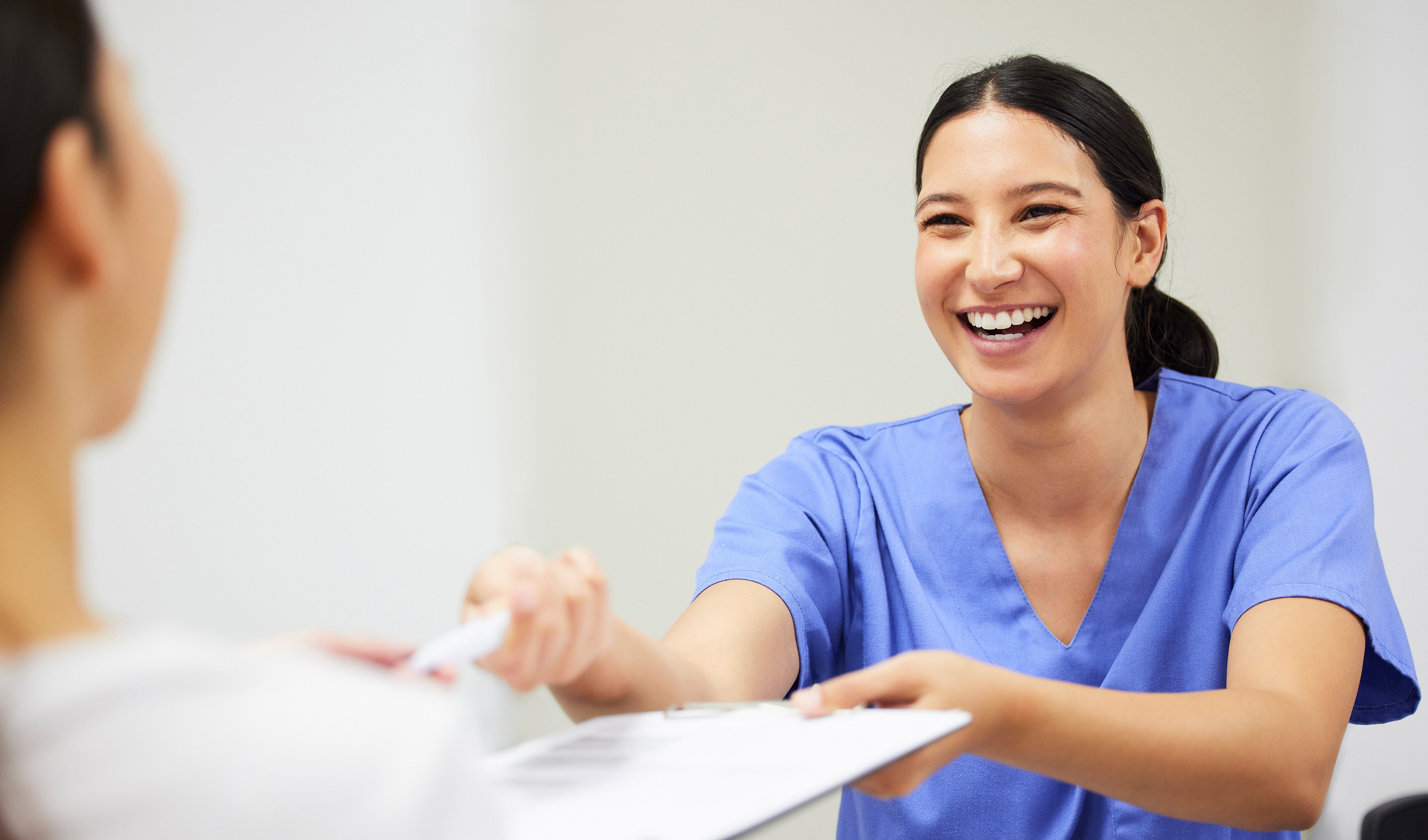 A nurse hands papers and a pen to a patient