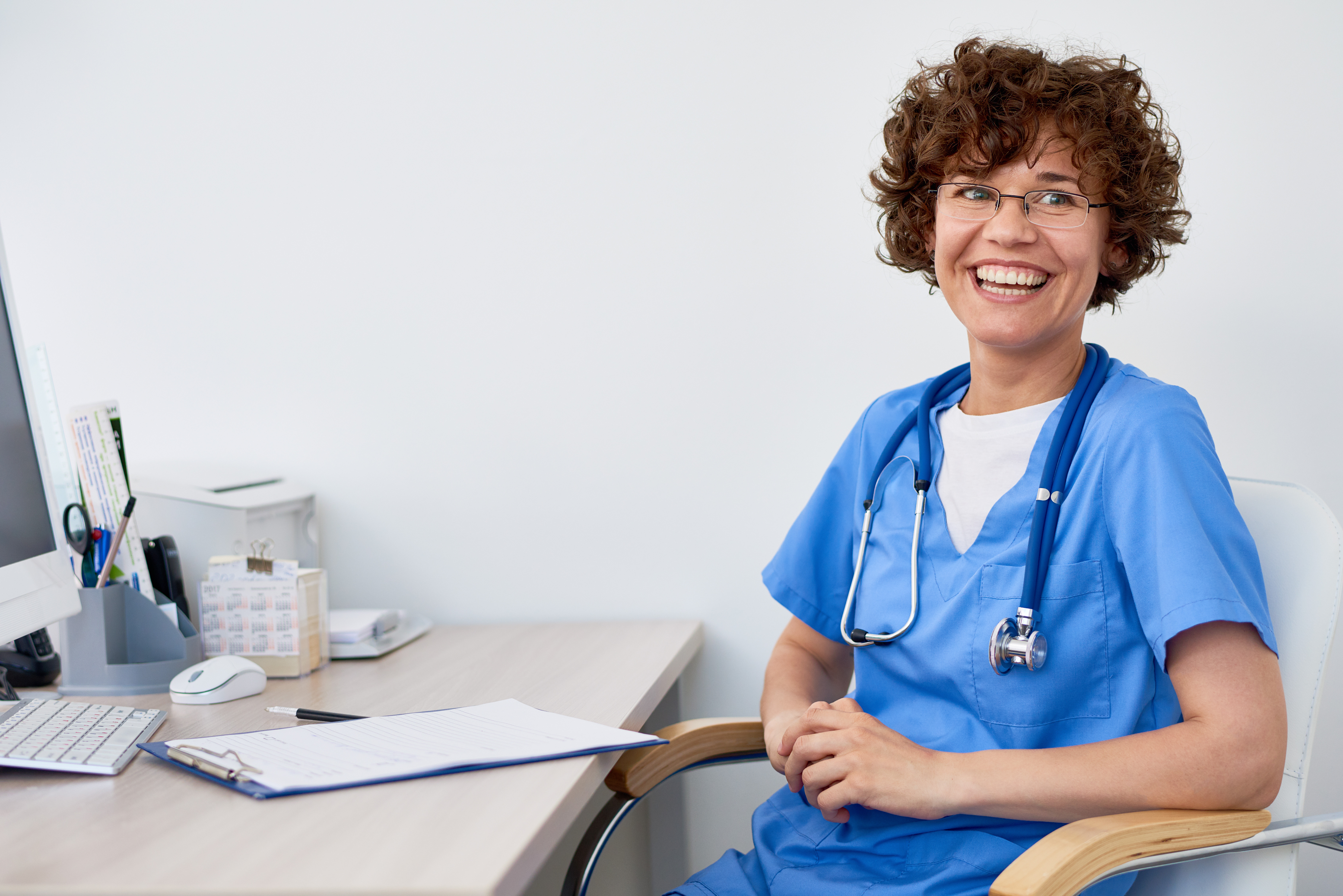 Smiling doctor sitting at desk in office.