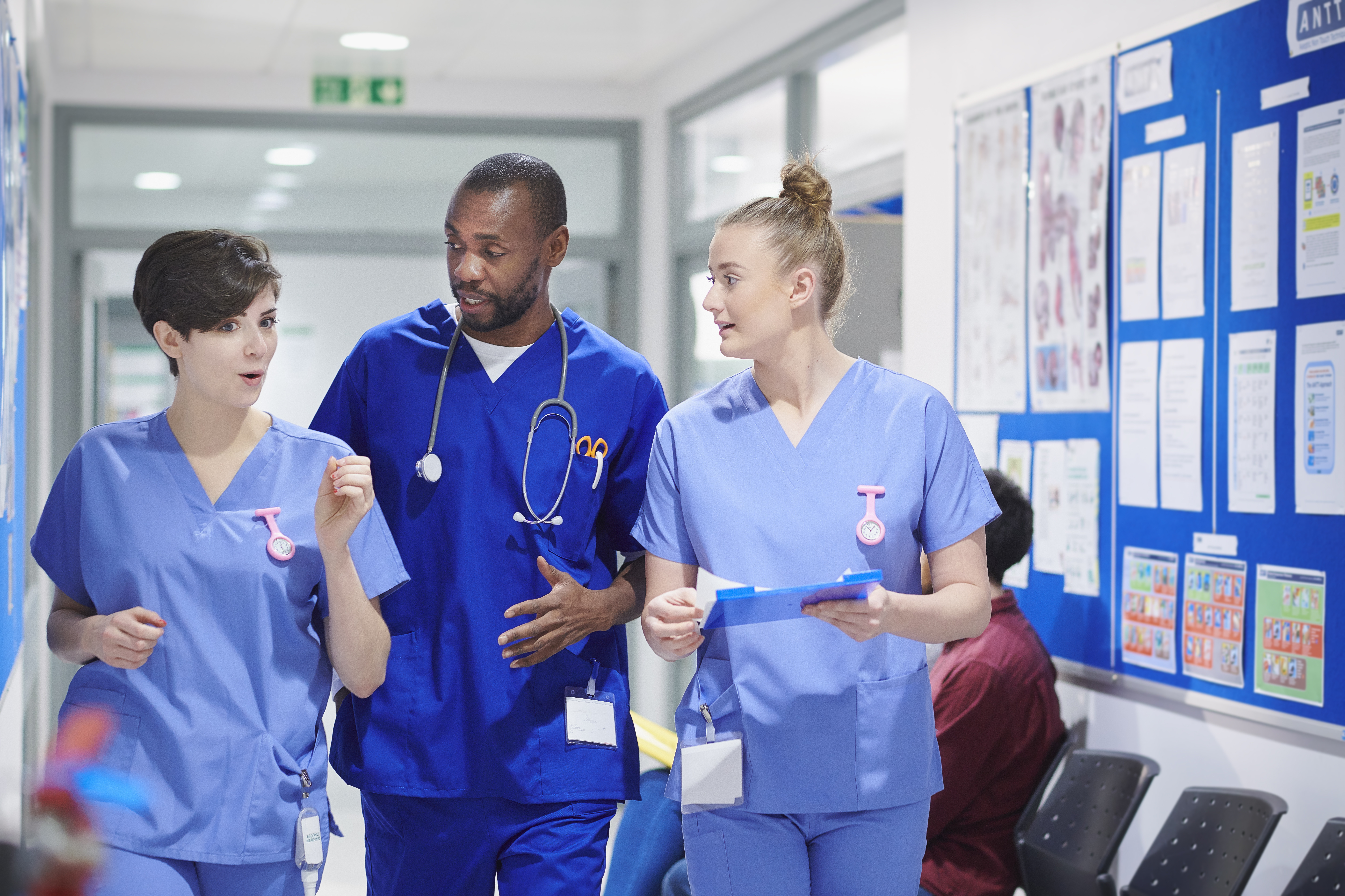 Three nurses chatting in a hospital corridor